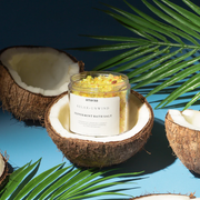 Peppermint bath salt jar in coconut halves with tropical leaves on blue background